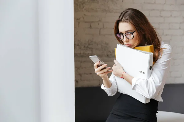 Sad tired business woman indoors using mobile phone — Stock Photo, Image