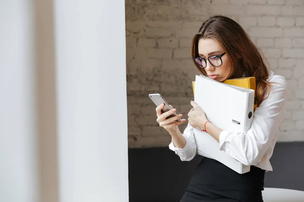 Sad tired business woman indoors using mobile phone — Stock Photo, Image