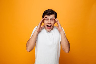 Şaşırmış adam kafa tutan ve kameraya bakarak t-shirt