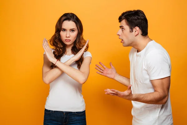 Недовольный мужчина кричит на свою девушку, которая показывает стоп-жест — стоковое фото