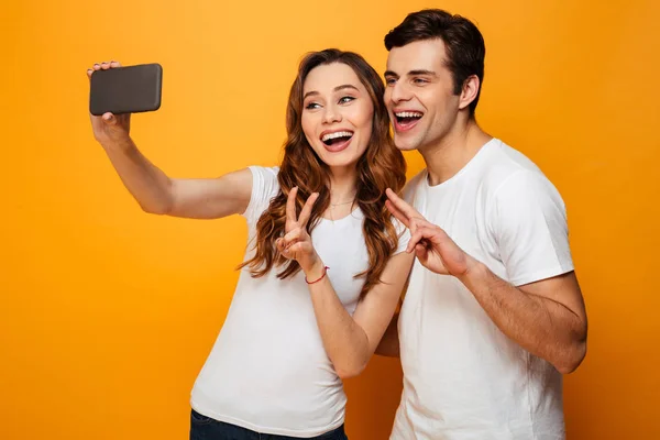 Jovens amigos encantadores sorrindo e fazendo selfie no smartphone whi — Fotografia de Stock