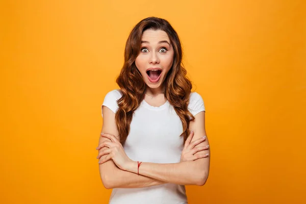 Überraschte brünette Frau im T-Shirt posiert mit verschränkten Armen — Stockfoto