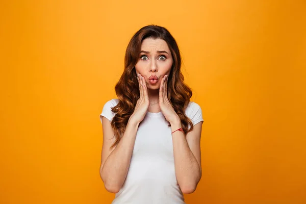 Überraschte brünette Frau im T-Shirt hält ihre Wangen — Stockfoto