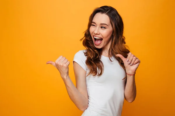 Feliz gritando mulher morena em t-shirt olhando e apontando para longe — Fotografia de Stock