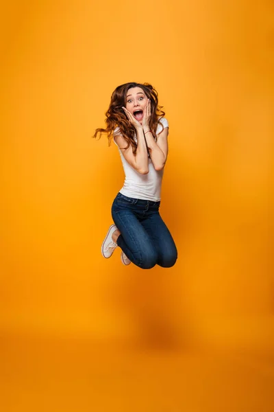 Imagen completa de Mujer morena sorprendida en camiseta saltando —  Fotos de Stock