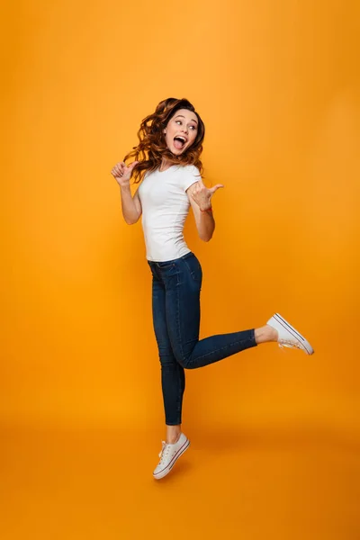 Full length image of Happy brunette woman in t-shirt jumping — Stock Photo, Image