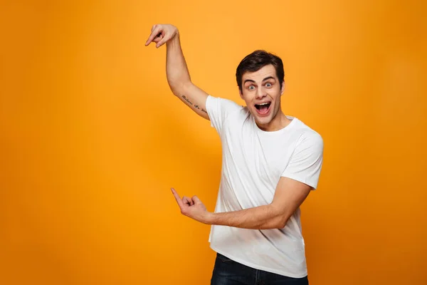 Surprised happy man in t-shirt pointing on copyspace — Stock Photo, Image