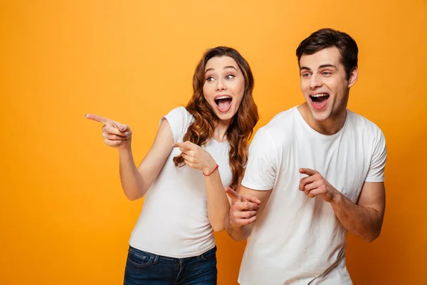 Feliz gritando jovem lindo casal apontando e olhando para longe — Fotografia de Stock