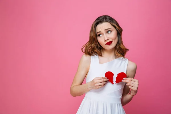 Confused woman holding broken heart. Looking aside. — Stock Photo, Image