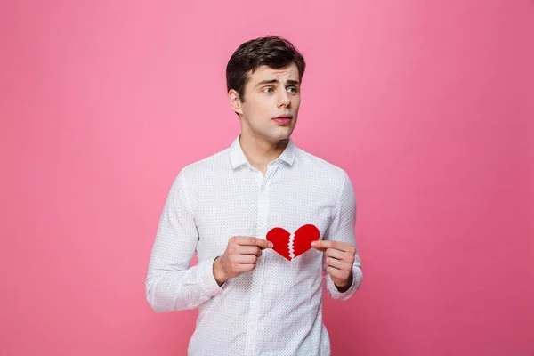 Sad man håller brustet hjärta. Tittar åt sidan. — Stockfoto