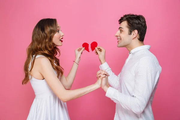 Happy älskande par hålla två halvor av hjärtat — Stockfoto
