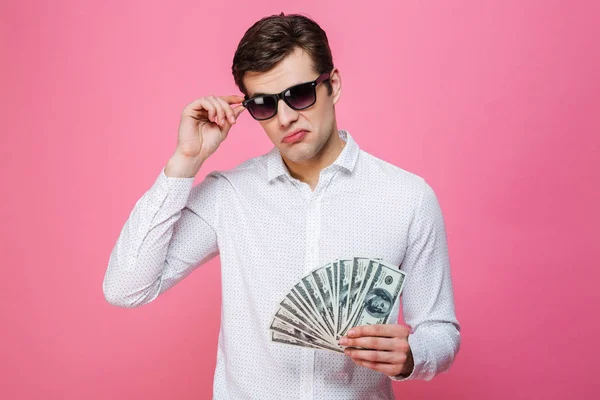 Allvarlig stilig man bär solglasögon håller pengar — Stockfoto