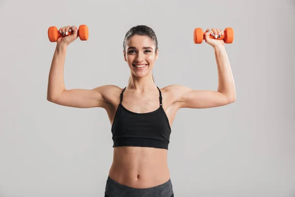 Image of happy strong woman putting small dumbbells up in air is — Stock Photo, Image