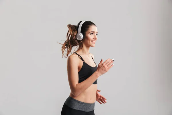 Cropped image of sporty woman in tracksuit running and listening — Stock Photo, Image