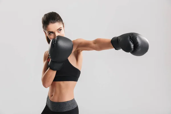 Serio morena fitness mujer entrenamiento en guantes de boxeo mientras l — Foto de Stock