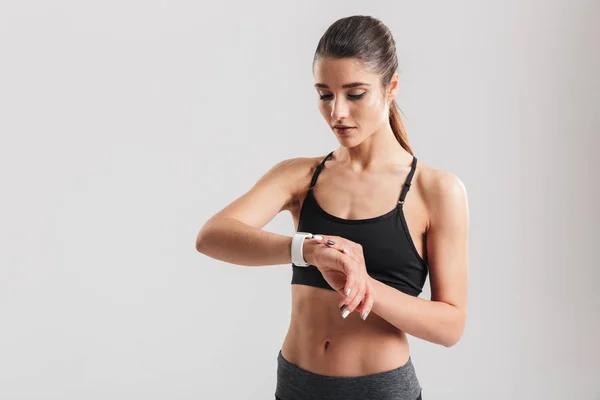 Foto de mujer atlética mirando reloj de pulsera y calculando ti —  Fotos de Stock