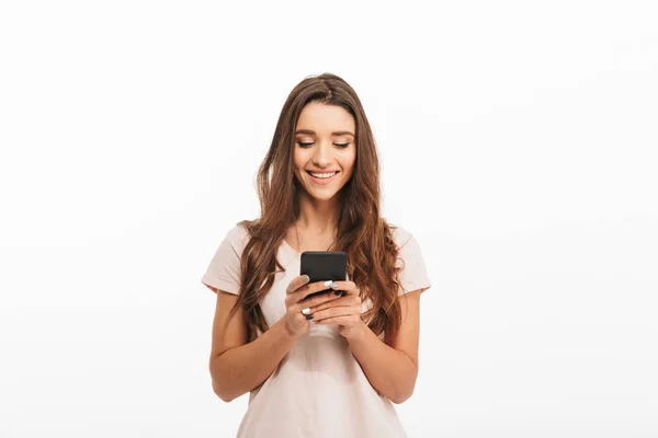 Femme brune joyeuse en t-shirt écrivant un message sur smartphone — Photo