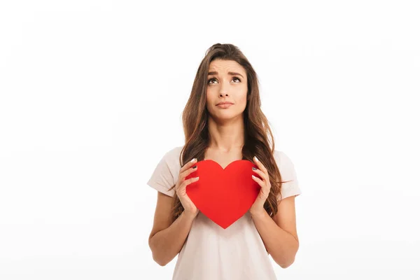 Upset woman in t-shirt holding paper heart and looking up — Stock Photo, Image