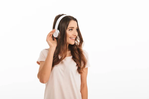 Mujer morena agradable en camiseta escuchando música con auriculares —  Fotos de Stock