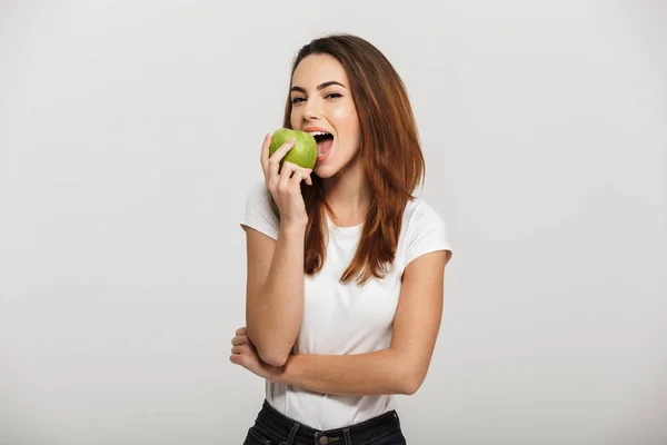 Portret van een vrolijke jonge vrouw die groene appel eet — Stockfoto