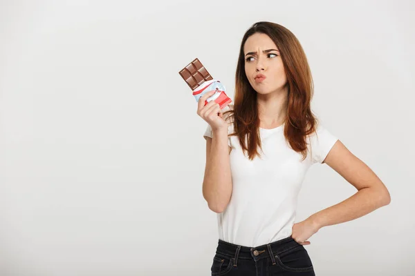 Retrato de uma jovem pensativa olhando para barra de chocolate — Fotografia de Stock