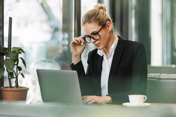 Concentrated blonde business woman using laptop computer.