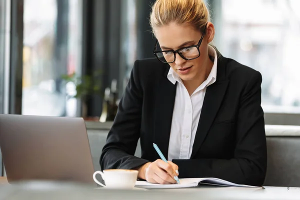 Konzentrierte Geschäftsfrau schreibt Notizen in Notizbuch. — Stockfoto