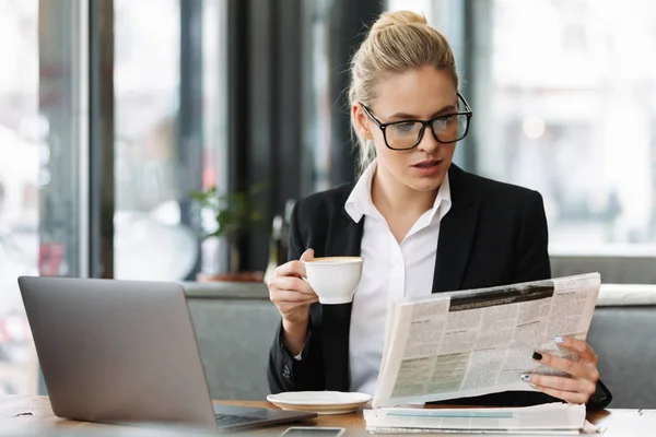 Serious business woman reading newspaper.