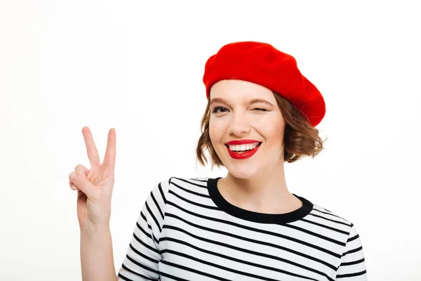 Young cute woman winking and showing peace gesture. — Stock Photo, Image