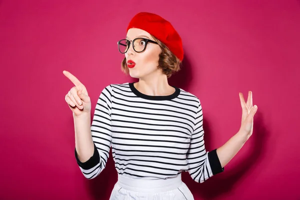 Shocked ginger woman in eyeglasses pointing and looking away — Stock Photo, Image