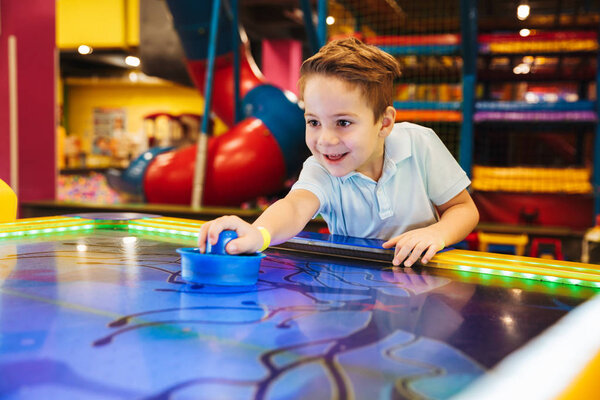 Joyful little boy playing air hockey