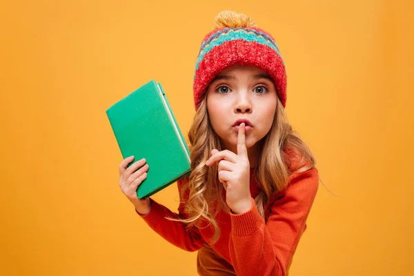 Gåtfulla ung flicka i tröja och hatt håller bok — Stockfoto