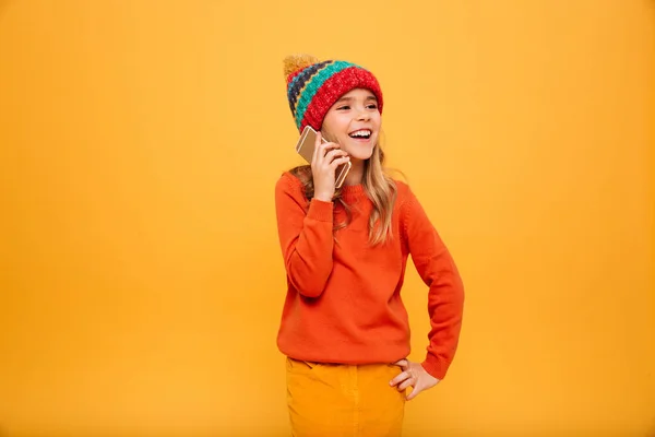 Veselá dívka v svetr a čepice s rukou na boku — Stock fotografie