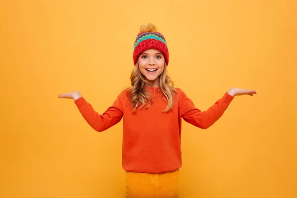 Ευτυχισμένη κοπέλα με πουλόβερ και καπέλο σηκώνει τους ώμους τους ώμους της — Φωτογραφία Αρχείου