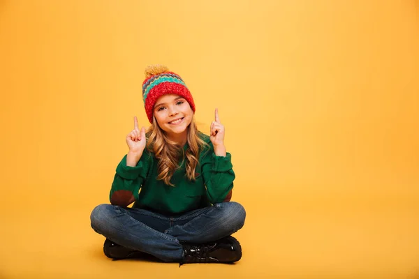 セーターと帽子が床に座って幸せな女の子 — ストック写真