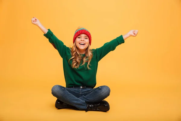 Allegro Giovane ragazza in maglione e cappello seduto sul pavimento — Foto Stock