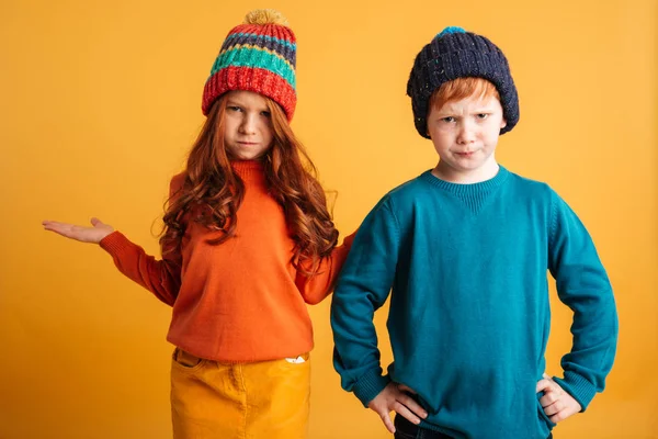 Dos pequeños niños pelirrojos confusos usando sombreros calientes . —  Fotos de Stock