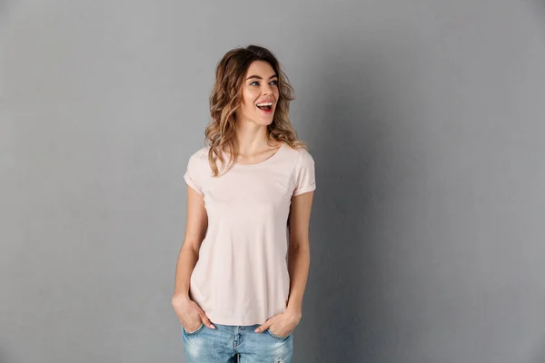 Šťastná žena v tričko pózuje s rukama v kapsách — Stock fotografie