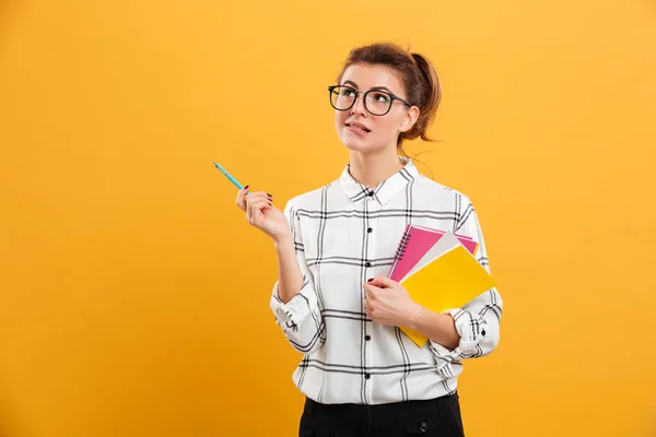 Foto einer jungen Frau, die beim Stehen mit Schulbüchern zur Seite schaut — Stockfoto