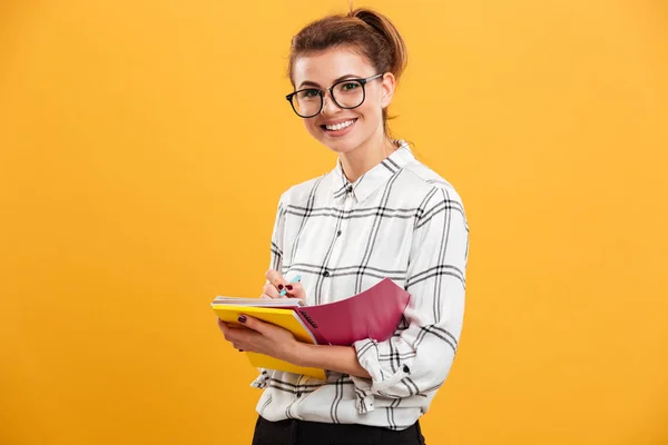 Foto einer jungen gebildeten Frau, die in die Kamera blickt und aufschreibt — Stockfoto