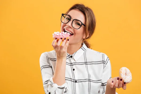 Portrait of hungry brunette woman in plaid shirt eating tasty do — Stock Photo, Image