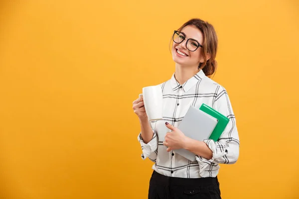 Foto di giovane donna che guarda sulla macchina fotografica mentre tiene libri e c — Foto Stock