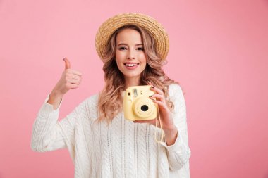 Pretty young woman holding camera showing thumbs up. clipart