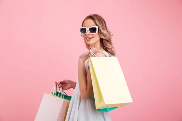 Mutlu genç kadın alışveriş torbaları tutan güneş gözlüğü takıyor. — Stok fotoğraf