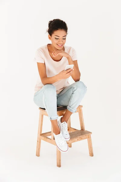 Retrato de mulher mulata em casual sentado na cadeira e segurando — Fotografia de Stock