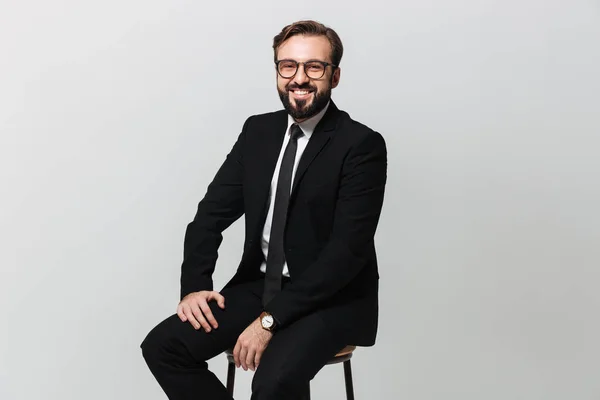 Portrait of happy office worker in black suit smiling while sitt — Stock Photo, Image