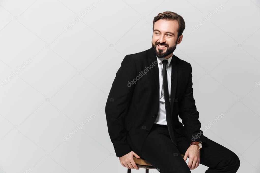 Portrait of happy office worker in black suit smiling while sitt