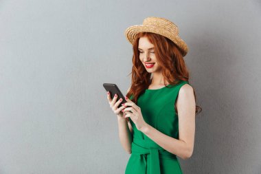 Kızıl saçlı genç neşeli kadın cep telefonuyla sohbet.