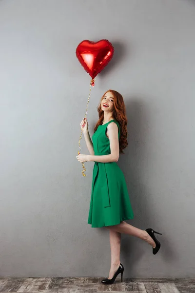 Sonriente pelirroja joven sosteniendo el globo del corazón . —  Fotos de Stock