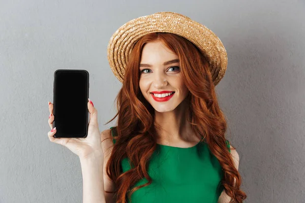 Рыжая молодая счастливая женщина показывает дисплей мобильного телефона . — стоковое фото